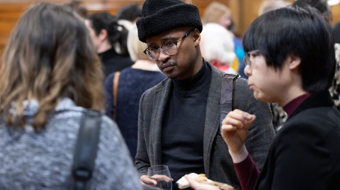 Black man with hat talking to East Asian student after the lecture