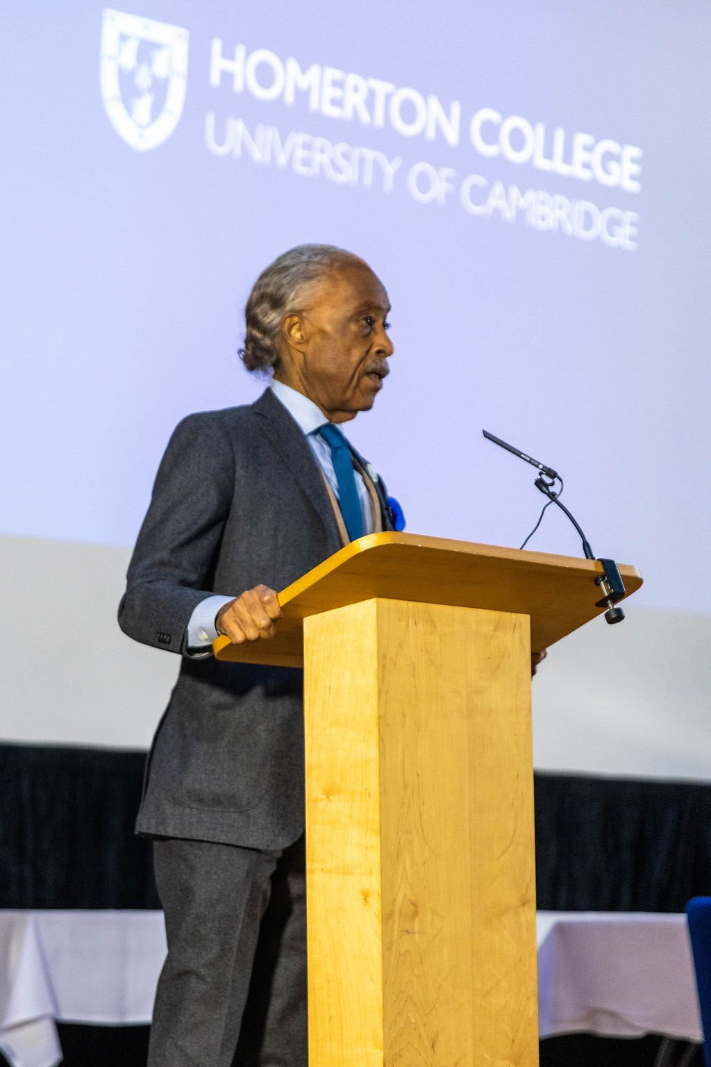 Rev Al Sharpton speaking from a lectern at Homerton College
